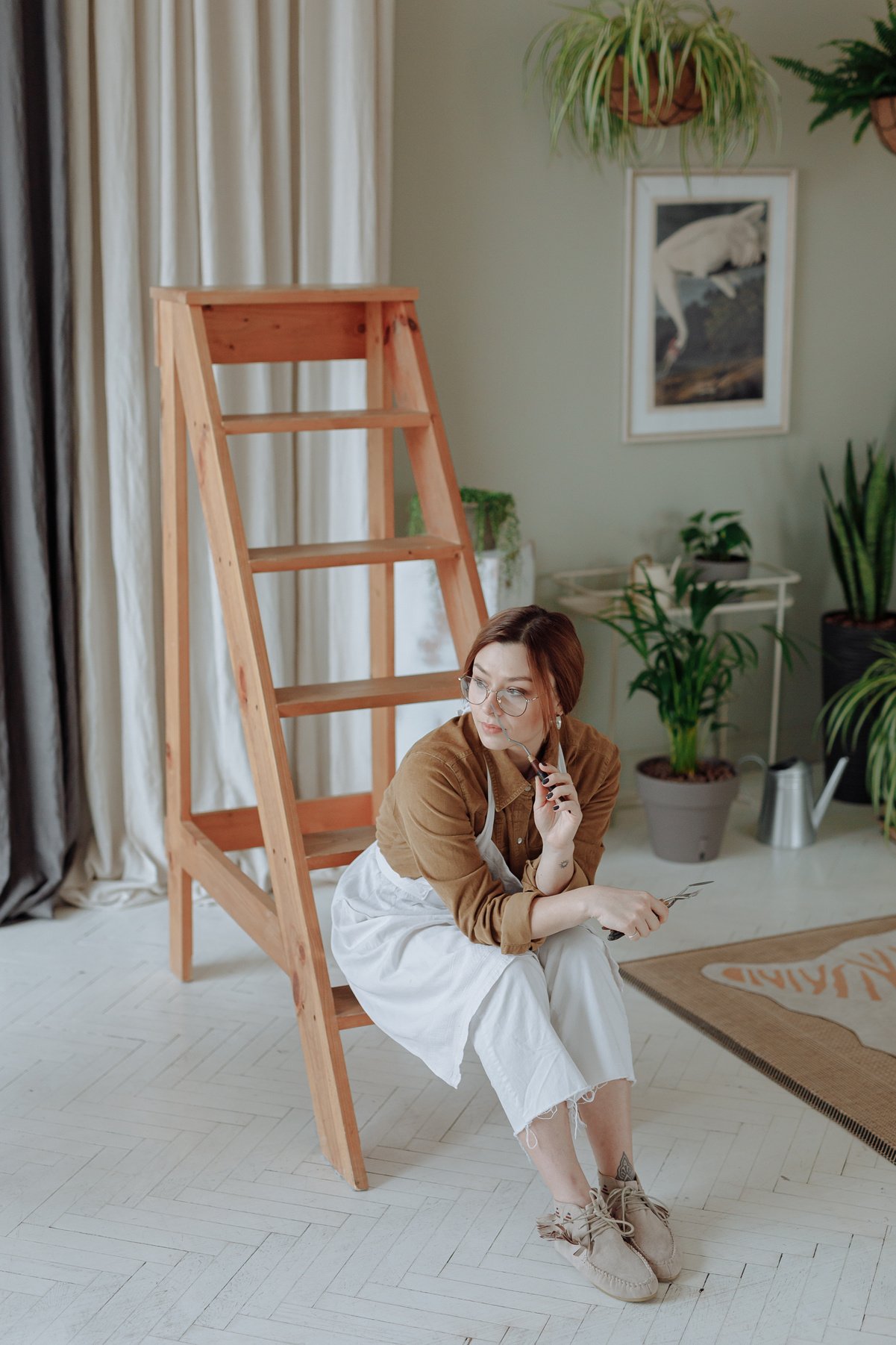 Woman Looking Afar While Sitting on Wooden Ladder